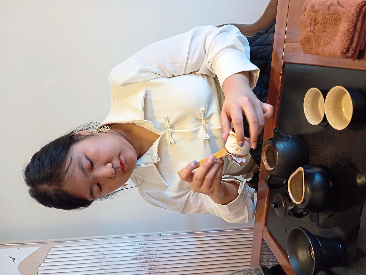 Chan places tea leaves into the teapot with bamboo tongs