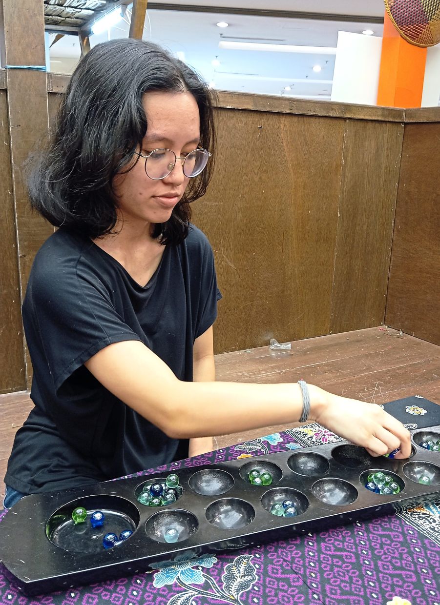 Siew indulges in traditional games such as congkak as a break from the coding she does as a computer science major.