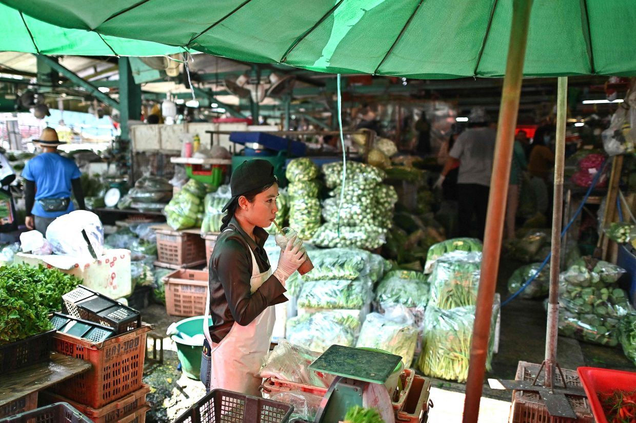 A vegetable vendor drinks a cold drink at Khlong Toei Market, the biggest fresh market in Bangkok on Thursday, April 25, 2024. Extreme heat is scorching parts of South and South-East Asia, prompting health warnings from authorities as high temperatures are recorded across the region. - AFP