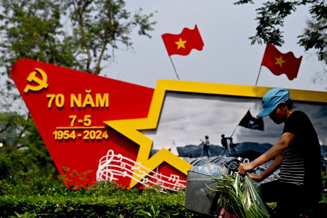 A woman rides a bicycle past a structure celebrating the 70th anniversary of Vietnam's May 7, 1954, Dien Bien Phu victory against French colonial forces in Hanoi on Thursday, April 25, 2024. AFP