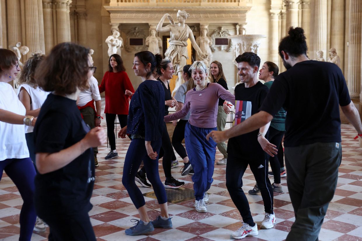 Members of staff of the Louvre Museum participate in a disco dance class as part of the dress rehearsal of 'Run In The Louvre'. Photo: Reuters 