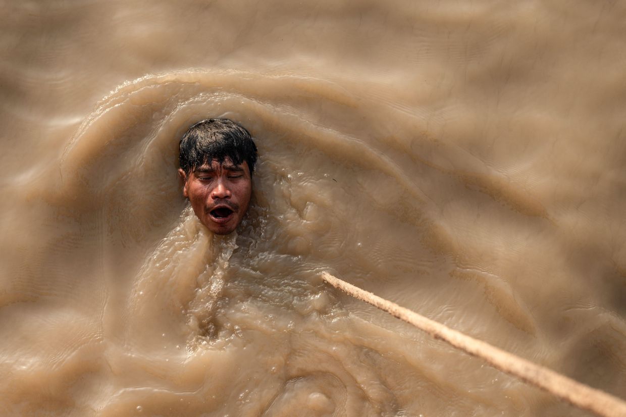 Than Nyunt swimming after a dive to recover a sunken ship in the Yangon River in Yangon. - AFP