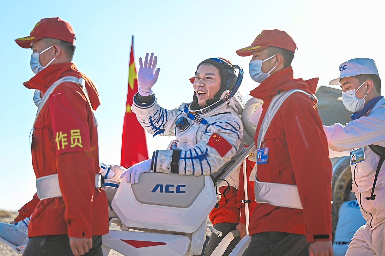 Mission commander Tang Hongbo, waving as he is carried out of the capsule.