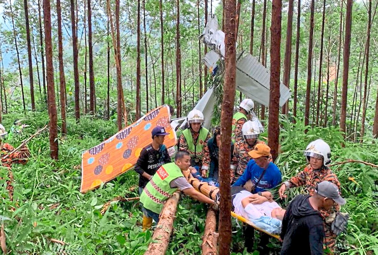 Successful operation: Rescuers extricating the two victims from the wreckage. — Bernama