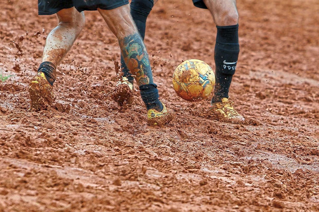 Locals play football in a dirt field in Sao Paulo, Brazil, on Feb 17. — AFP