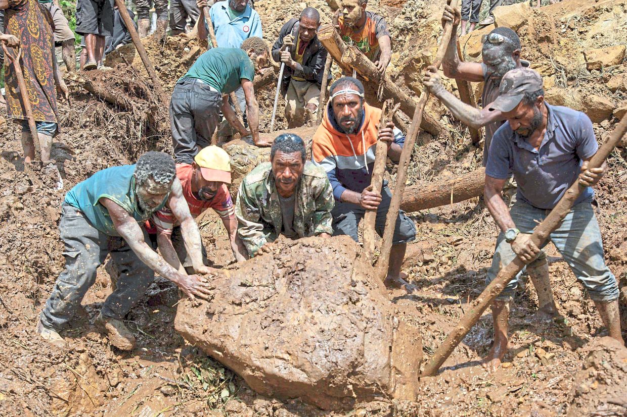 Locals digging at the site of the landslide at the same village. 