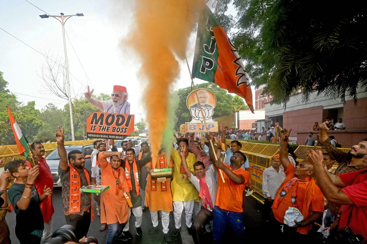Supporters of Narendra Modi, India's Prime Minister and leader of Bharatiya Janata Party (BJP) celebrate vote counting results for India's general election, at BJP headquarters in New Delhi on June 4, 2024. India's Hindu nationalist Prime Minister Narendra Modi and his allies were heading for victory in the country's general election count on Monday, June 4, but with a reduced parliamentary majority as the opposition surpassed expectations. - AFP