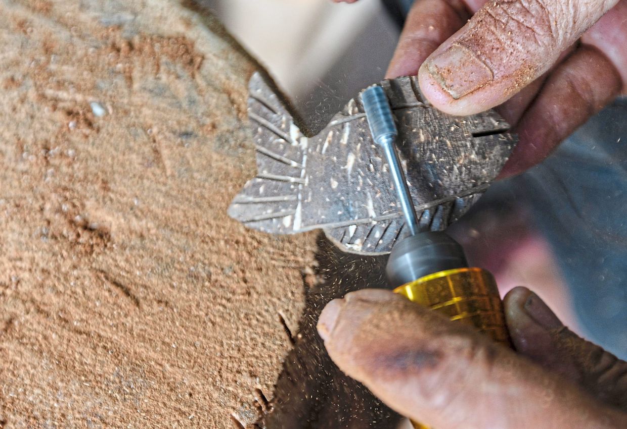  The craftsman using a small grinder to smoothen the surface of a piece of coconut shell. — Bernama