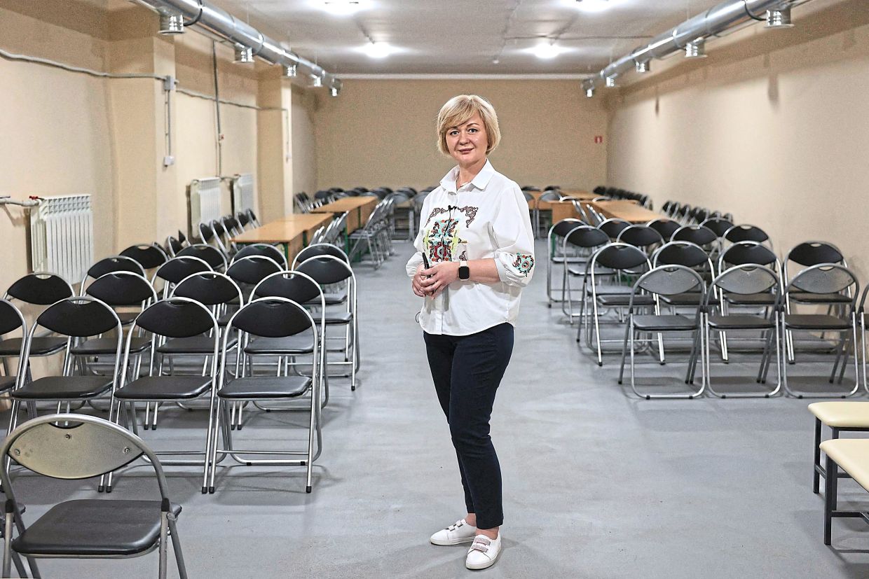 The principal of the 61st secondary school, Nelli Ustych, posing in the bomb shelter in the basement of her school in Kyiv. — AFP
