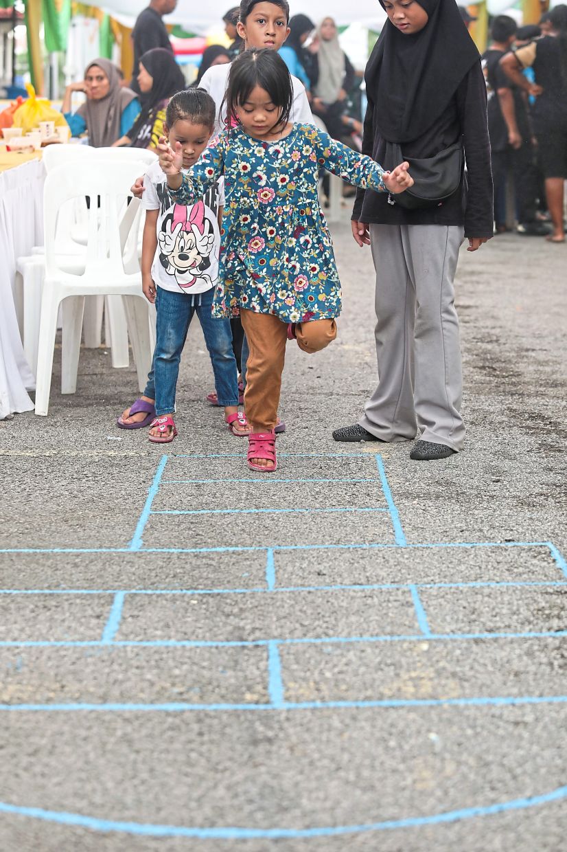 Children taking turns to play hopscotch, one of several games during the event.