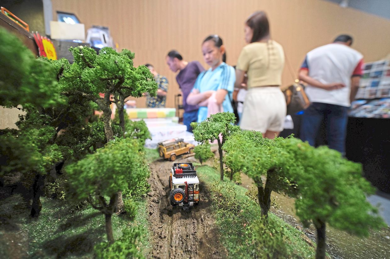 Diecast four-wheel drive vehicles “traversing” through a model of muddy slopes.