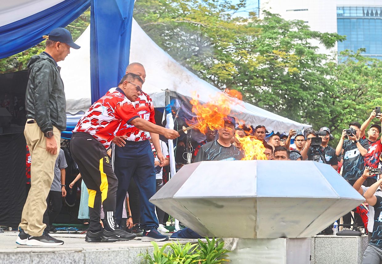 All set to go: Saifuddin Nasution (second, left) lighting the cauldron to launch the Safety Run.— LOW BOON TAT/The Star
