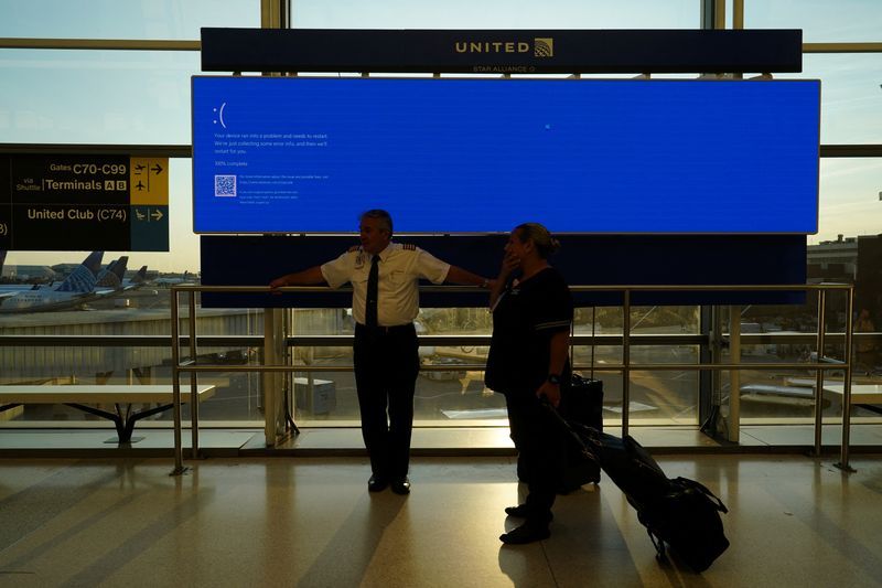 United Airlines employees wait by a departures monitor displaying a blue error screen also known as the Blue Screen of Death inside Terminal C in Newark International Airport after United Airlines and other airlines grounded flights due to a worldwide tech outage caused by an update to Crowdstrikes quotFalcon Sensorquot software which crashed Microsoft Windows systems in Newark New Jersey U.S. July 19 2024. REUTERSBing Guan