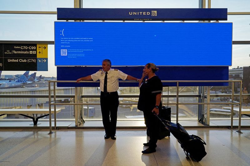 FILE PHOTO United Airlines employees wait by a departures monitor displaying a blue error screen also known as the ldquoBlue Screen of Deathrdquo inside Terminal C in Newark International Airport after United Airlines and other airlines grounded flights due to a worldwide tech outage caused by an update to CrowdStrikes quotFalcon Sensorquot software which crashed Microsoft Windows systems in Newark New Jersey U.S. July 19 2024. REUTERSBing GuanFile Photo    