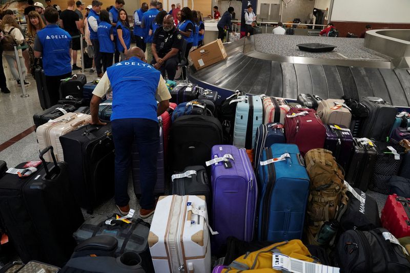 FILE PHOTO Delta employees are seen near luggage as people wait to retrieve their luggage after long delays following cyber outages affecting airlines at Hartsfield-Jackson Atlanta International Airport in Atlanta Georgia U.S. July 22 2024.   REUTERSMegan VarnerFile Photo