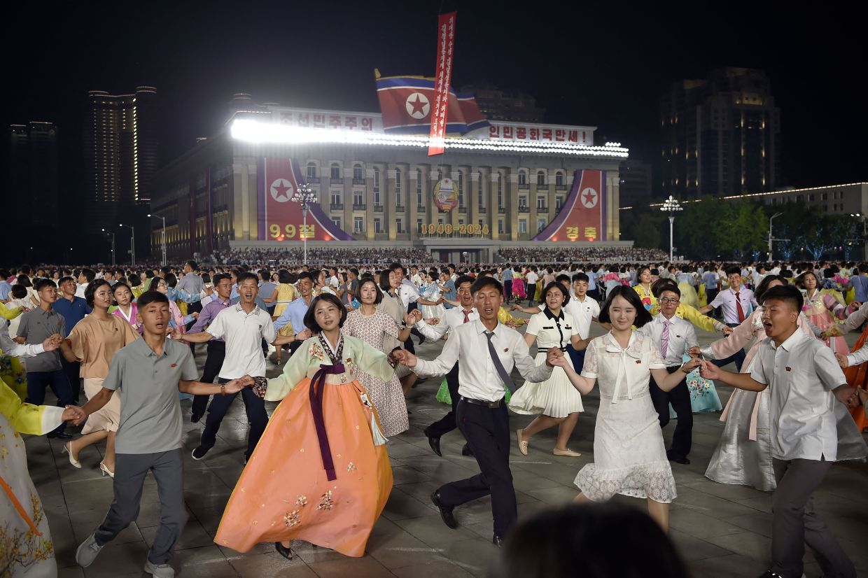 Participants take part during a celebration meeting and evening gala on the occasion of the 76th founding anniversary of North Korea at Kim Il Sung Square in Pyongyang. - AFP