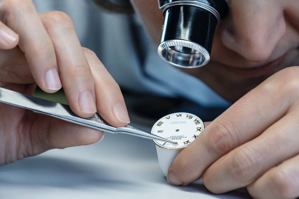 Fitting the Rolex crown applique on a dial by hand.
