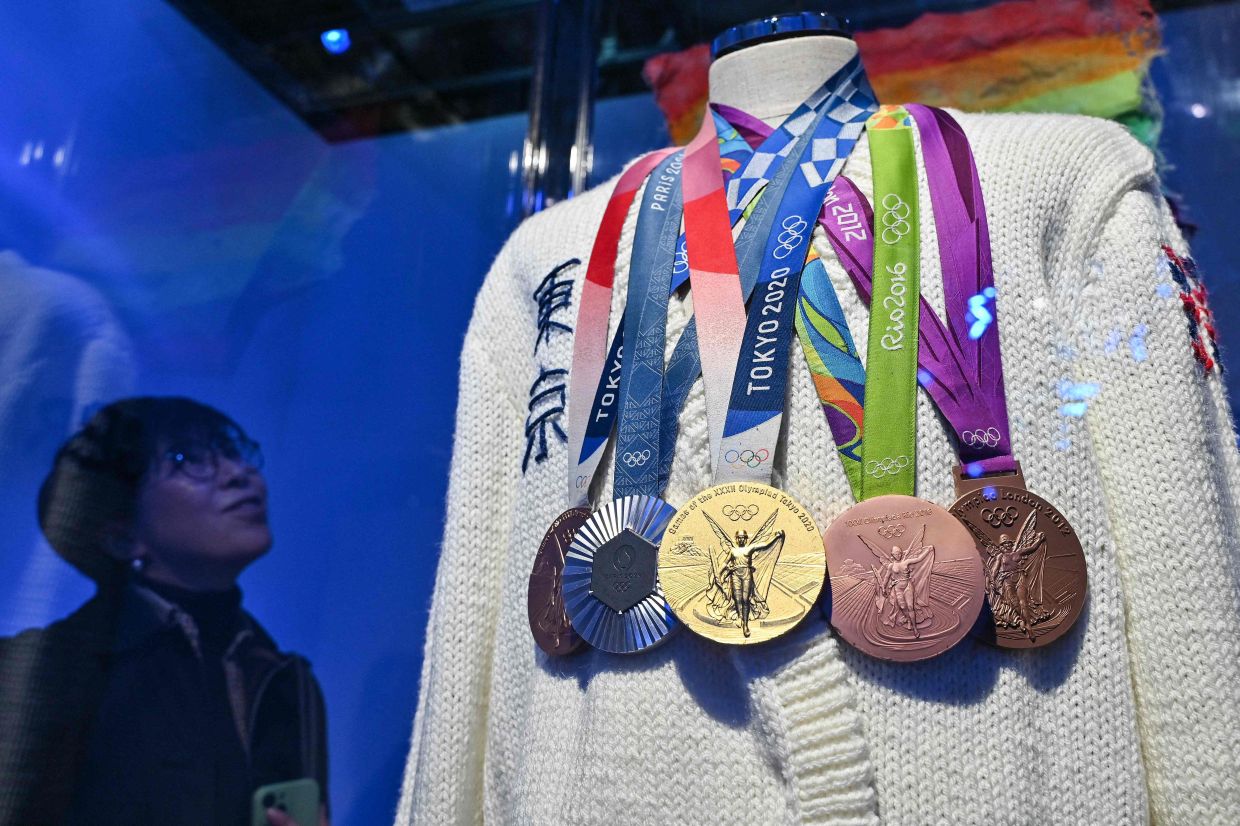 A visitor looks at a display of Daley's medals at a new exhibition showcasing his knitting creations.