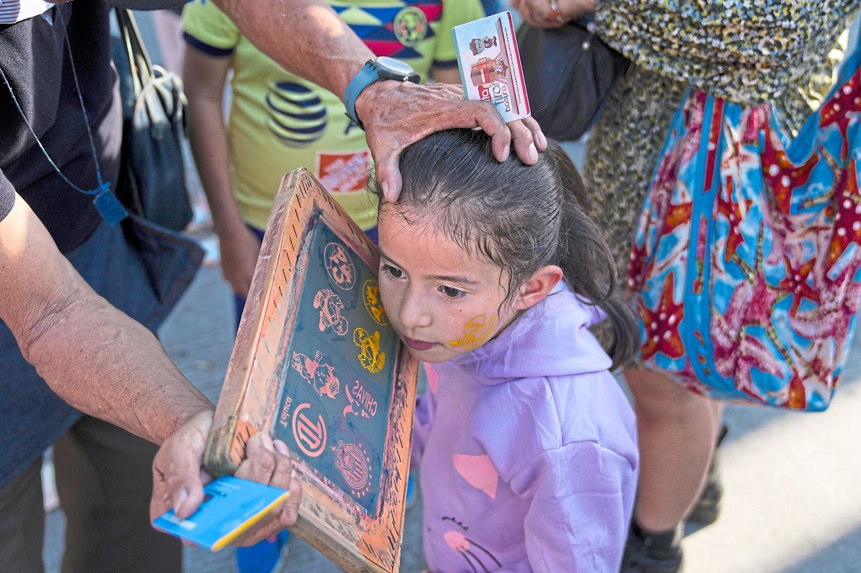 A young fan gets her face painted with her team’s logo before the America-Chivas match. — AP