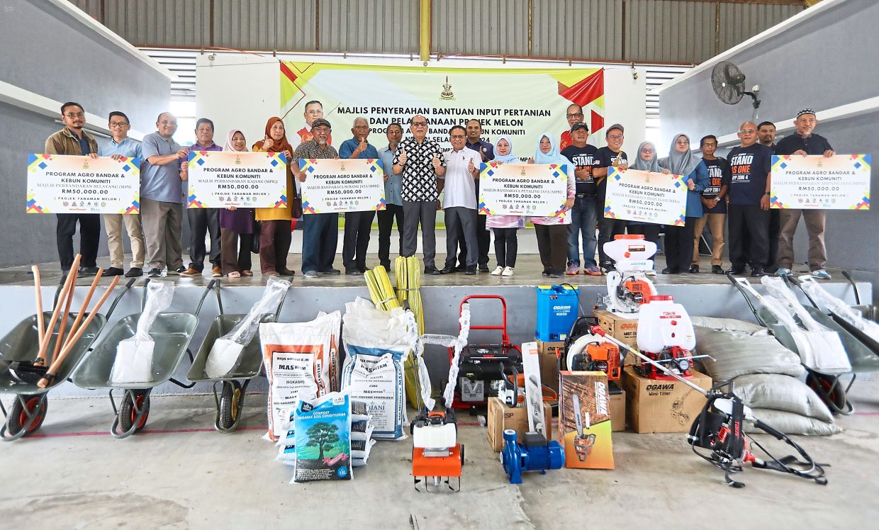 Izham (centre) with the aid recipients at the ceremony in Pandan Dalam. — SHAARI CHEMAT/The Star