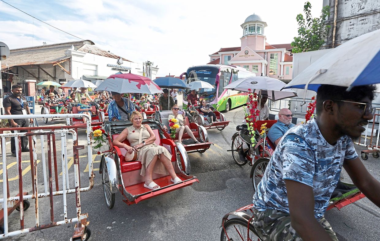 Passengers from a cruise ship enjoying a two-hour sightseeing tour on trishaw around George Town. Photos: — ZHAFARAN NASIB, LIM BENG TATT/The Star