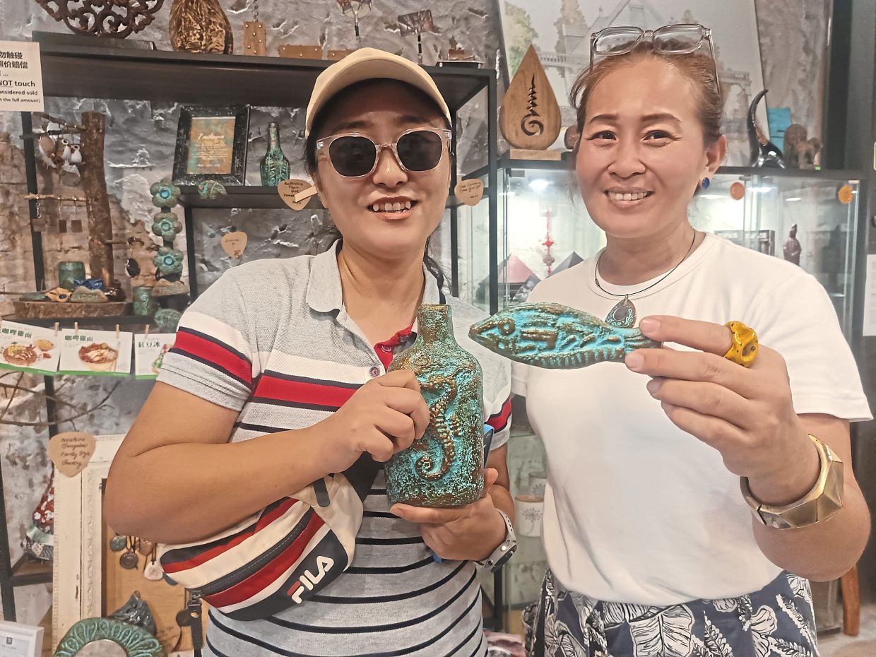 Lee (right) with Wang, who bought a fish-shaped fridge magnet and a whisky bottle repurposed as a vase with seahorse design.