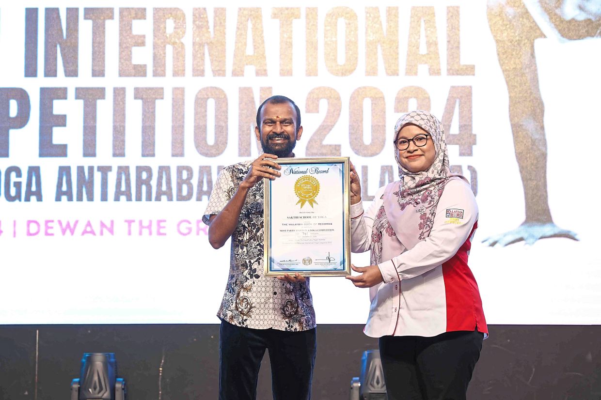 Malaysia Book of Records official Siti Hajar Johor (right) presenting Sakthi School of Yoga director SK Durai a certificate for the “Most Participants in a Yoga Competition”.