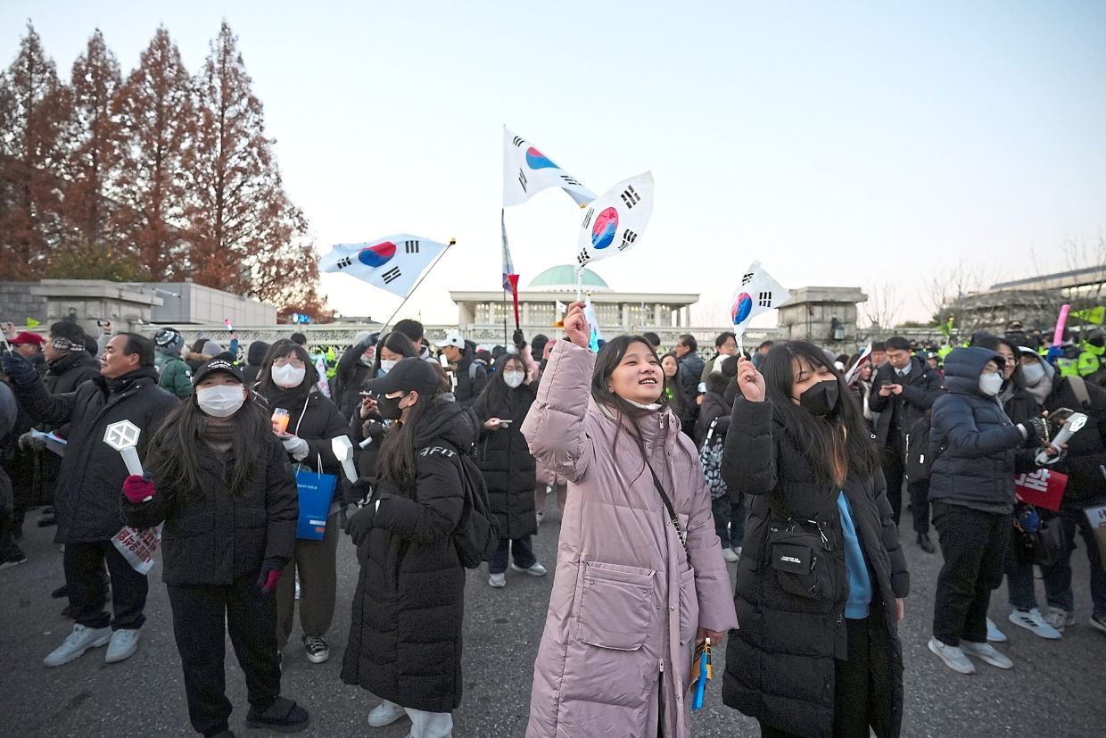 Protesters celebrating outside South Korea’s National Assembly in Seoul as a vote to impeach Yoon was announced. — ©2025 The New York Times Company
