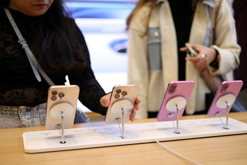 FILE PHOTO Women use Apple iPhone smartphones displayed at a store in London Britain October 6 2024. REUTERSHollie AdamsFile Photo
