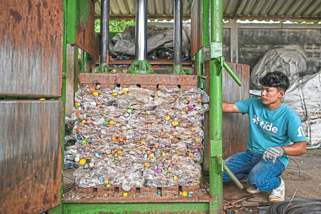 Crushing it: A Tide worker putting a stack of waste plastic PET bottles into a baling machine at Tide’s recovery facility in Ranong. — AFP