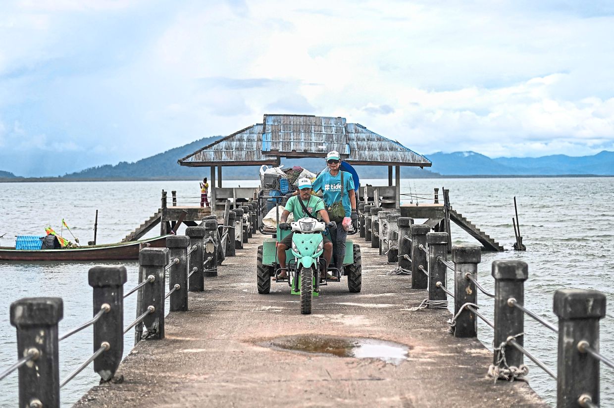 Whizzing through: Tide staff members transporting bags of plastic waste collected from a Moken fishing village to a temporary storage from the pier on Koh Chang. — AFP