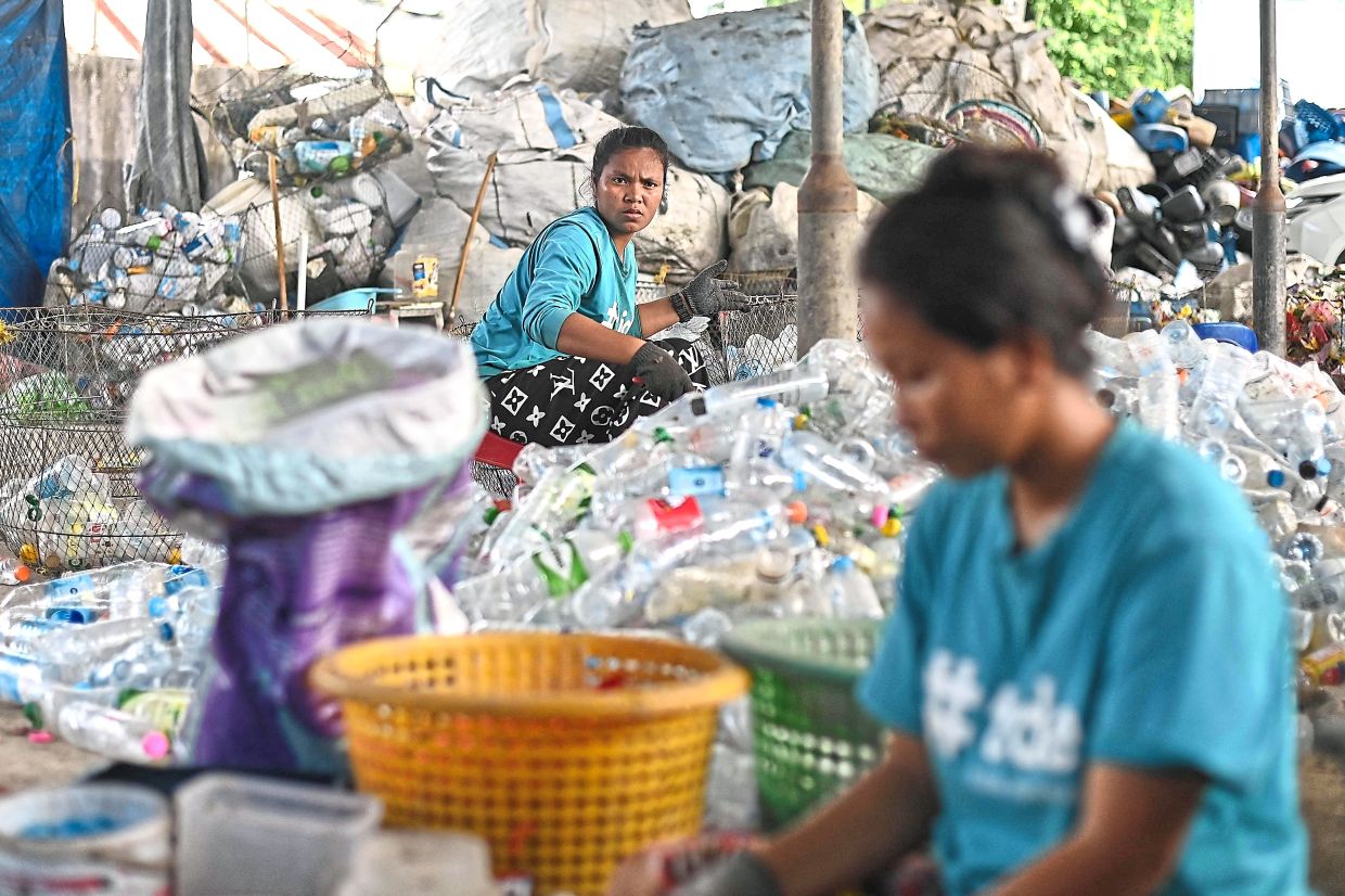 Painstaking endeavour: Tide staff members sorting plastic PET bottles at the Tide recovery facility in Ranong. — AFP