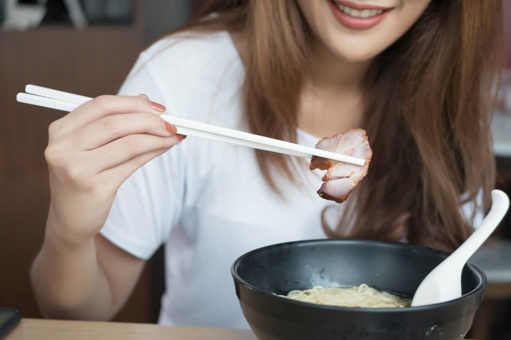 According to Buddhist principles, diners should avoid eating meat on the first and 15th days of the Lunar New Year holiday, so the barbecued pork this woman is eating with a bowl of noodles would be a no-no. -- Photo: Shutterstock via SCMP