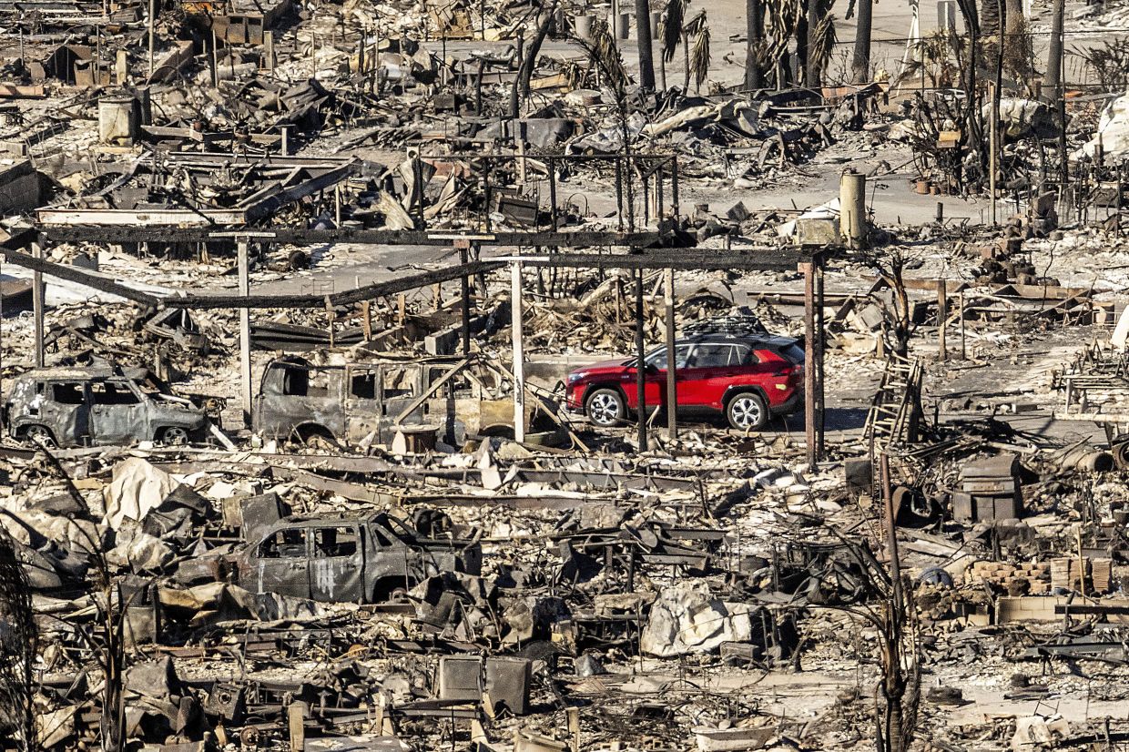 A car drives past homes and vehicles destroyed by the Palisades fire at the Pacific Palisades Bowl Mobile Estates in Los Angeles on Jan 12. Photo: AP 
