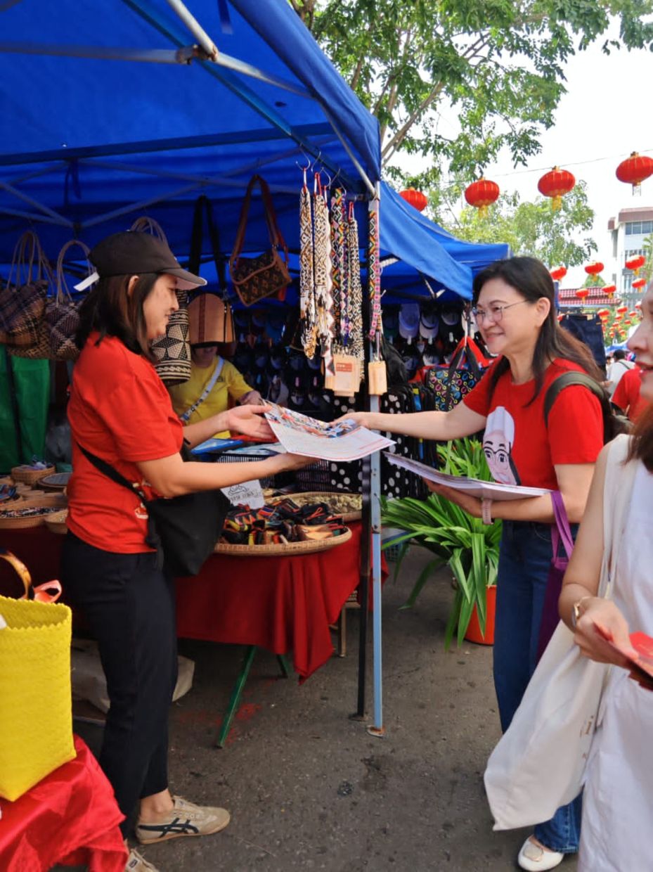 Political Secretary Vivien Lee (right) represented Api-Api assemblywoman Datuk Seri Christina Liew in the walkabout to distribute Liew's 2025 calendar .