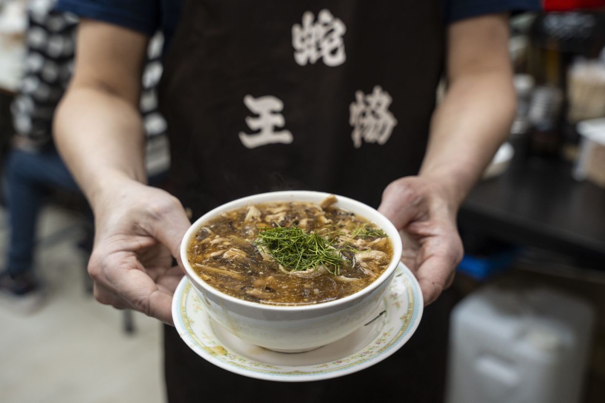 A waiter holds a bowl of snake soup at a restaurant in Hong Kong. - AP