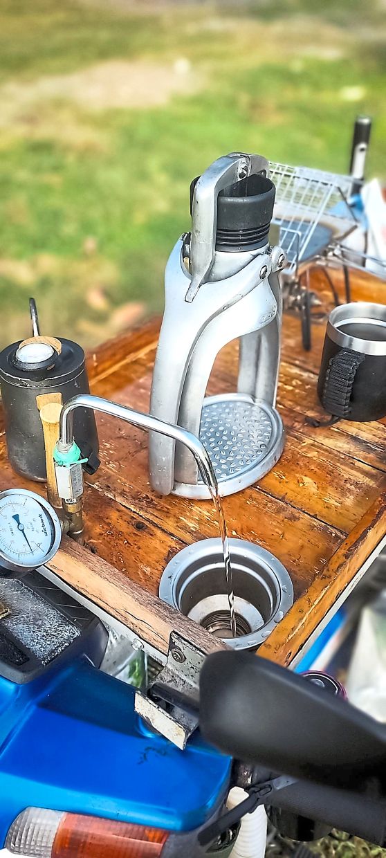 In the centre is a hand-operated espresso maker and to the left is the tap and sink on the motorcycle.