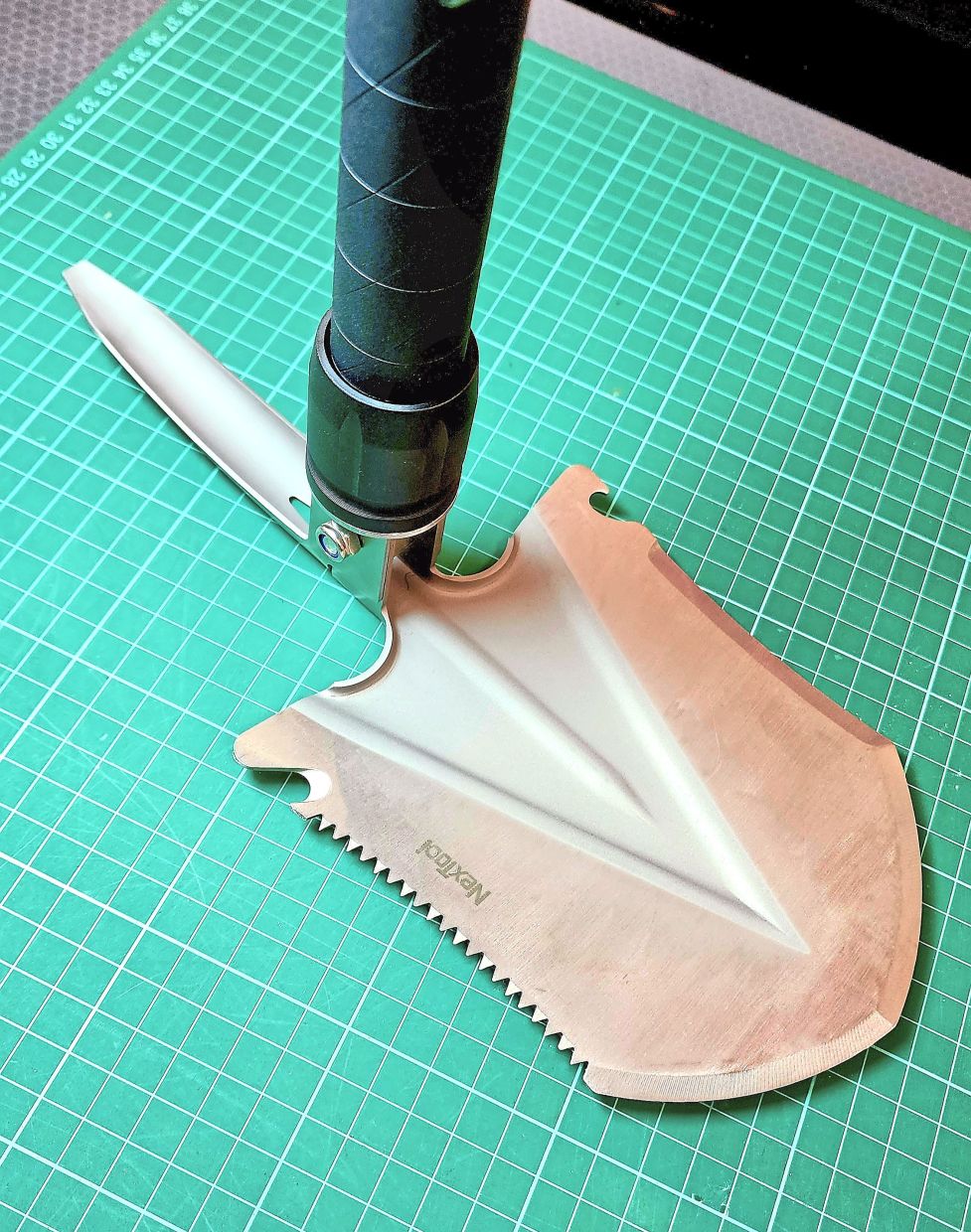 Multiple tools: A pointy pickaxe, a saw on one side and a blade on the other, with grooves for cutting rope and opening bottles.