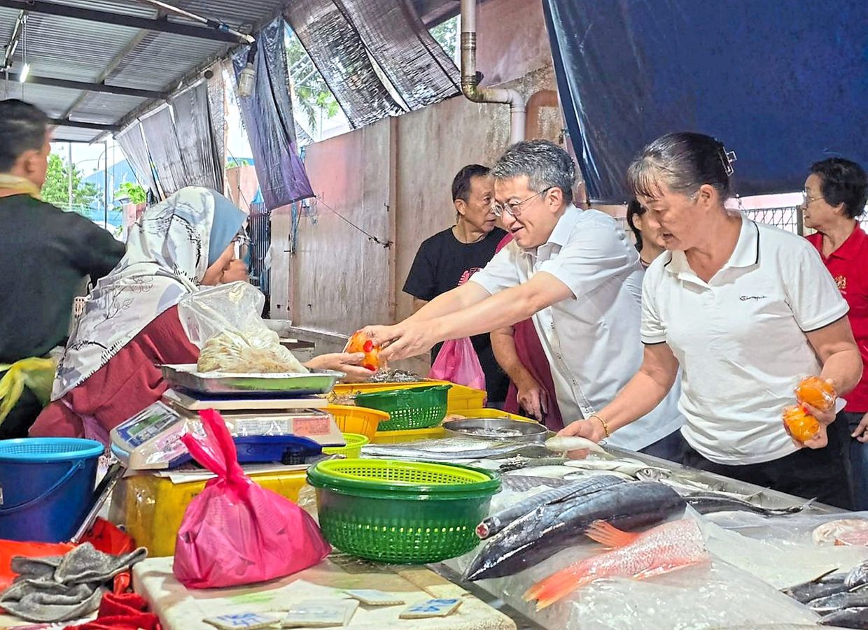 Liew handing out mandarin oranges at the market in Skudai.