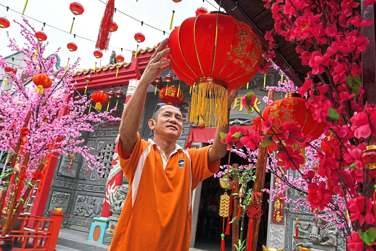 Chong inspects a lantern while decorating the temple.-Photos: Bernama