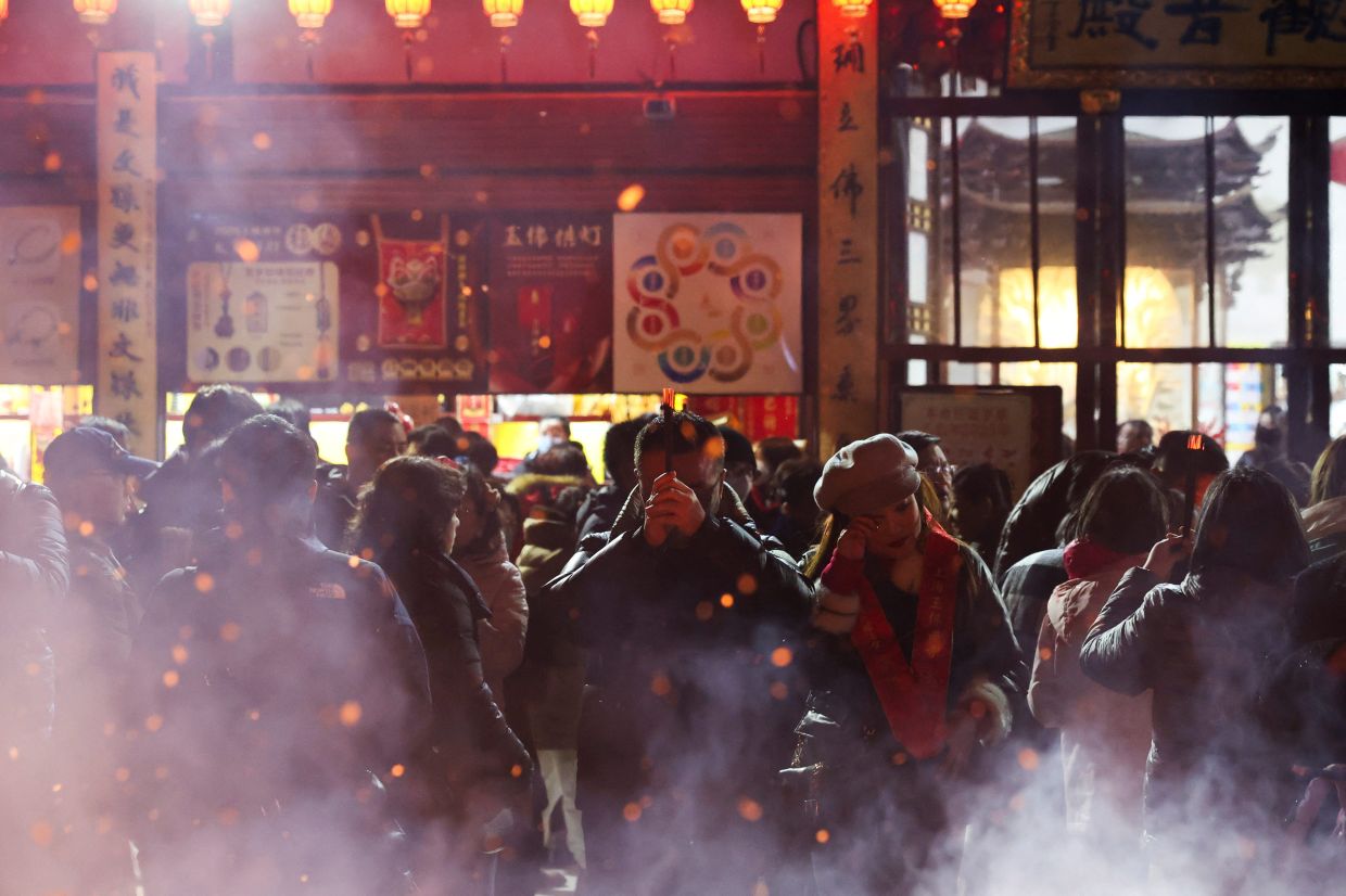 People perform a prayer at Jade Buddha Temple on Lunar New Year's Eve in Shanghai on Jan 28. Photo: Reuters 