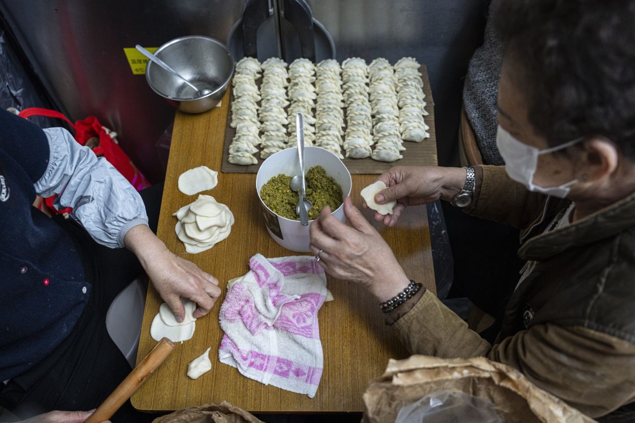 Staff members preparing crispy pastry dumplings with pistachio filling in the kitchen of a bakery in Hong Kong. - AP