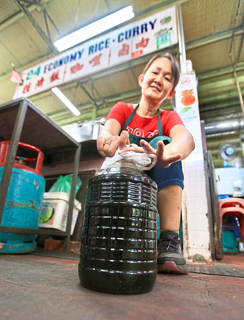 Lee pouring used cooking oil into a container before selling it to a recycling company.