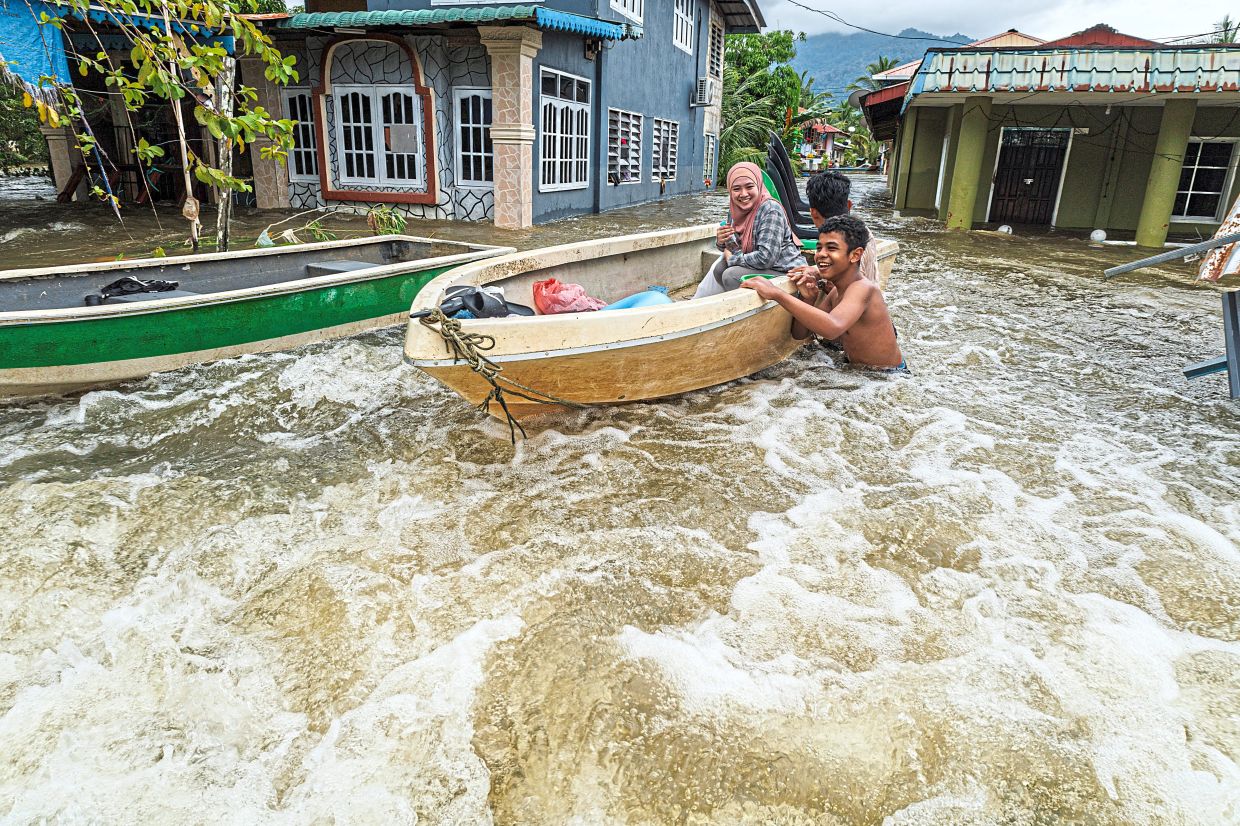 Water woes: A family evacuating their flooded home at Kampung Hilir Serian. — ZULAZHAR SHEBLEE/The Star