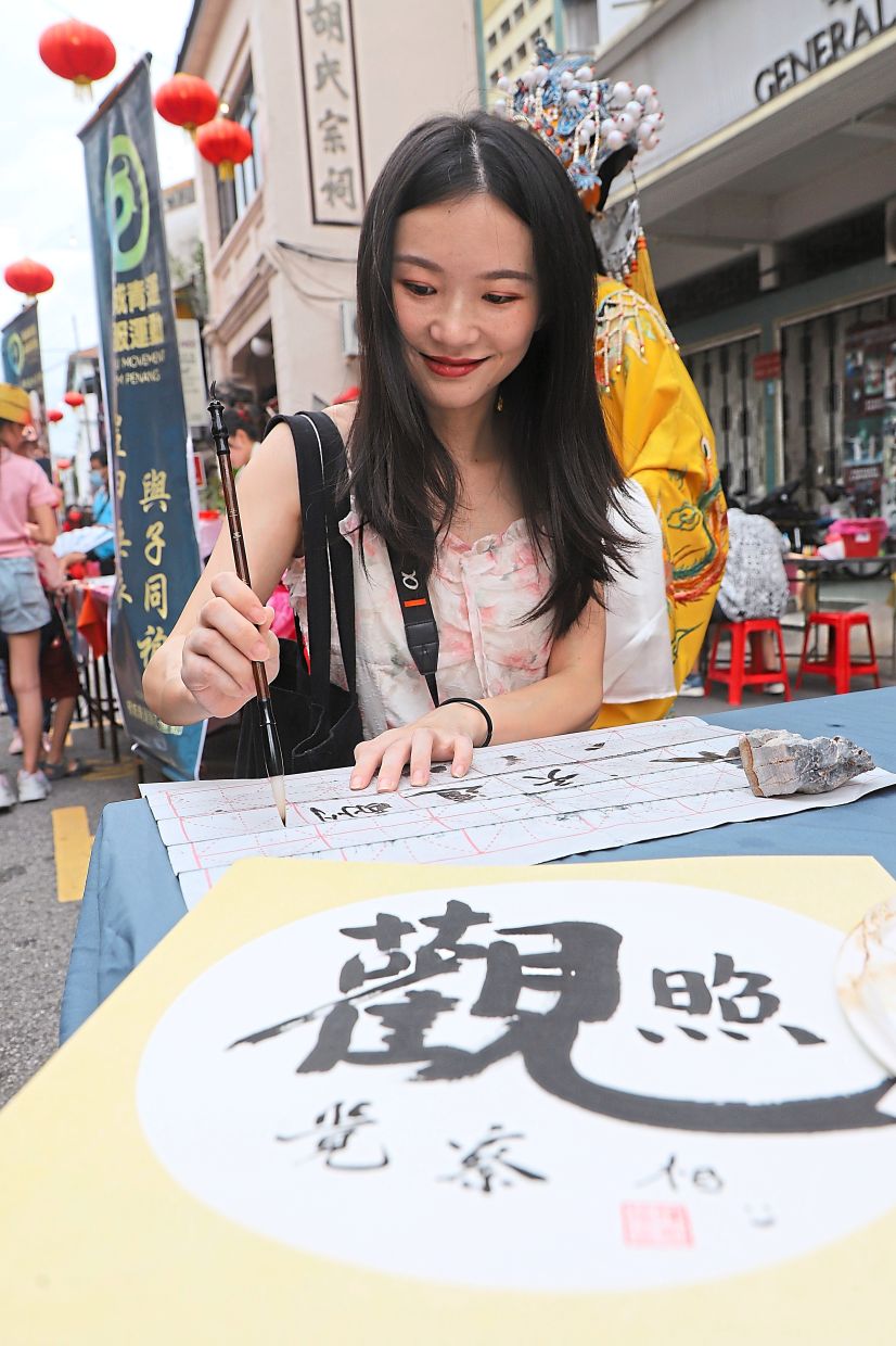 Ai trying her hand at Chinese calligraphy during a writing session.