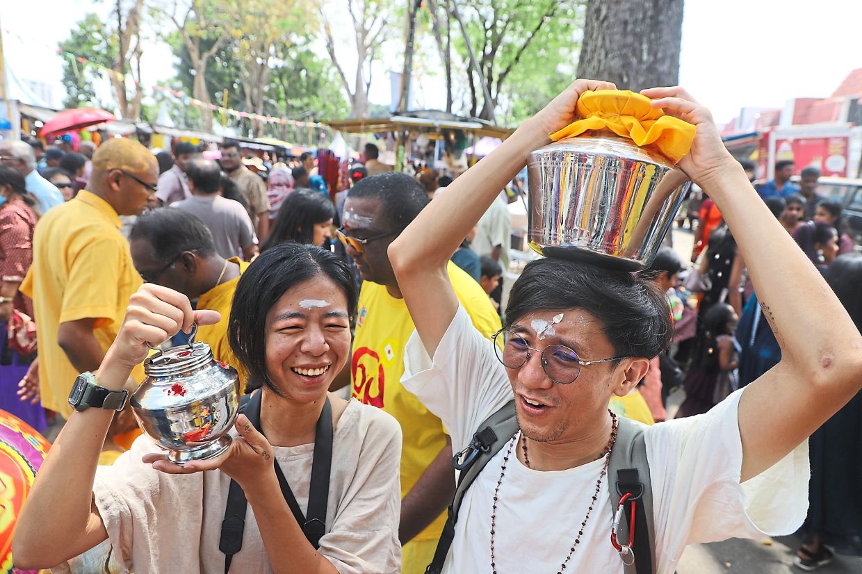 Devotees Oh Chin Eng (right) and his girlfriend Eunice Tan carrying ‘paal kodam’ (milk offerings) along Jalan Kebun Bunga during the Thaipusam festival.