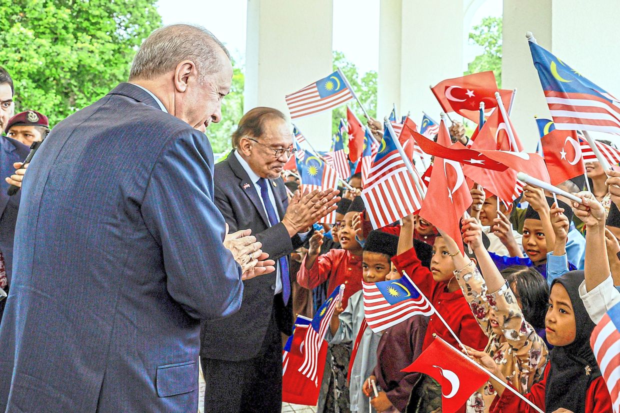 Warm welcome: Anwar and Erdogan greeting children waving Jalur Gemilang and Turkish national flags at the Seri Perdana Complex in Putrajaya. — Bernama