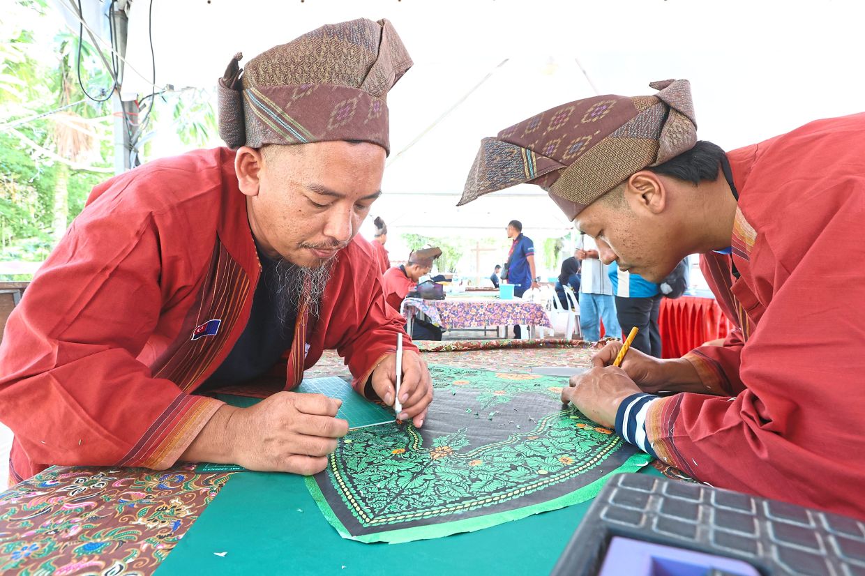 Local kite makers Muhammad Nasru Aiman Mohamed Zu, 35, (right) and Mohd Zunaidee Umar, 40, demonstrating their wau-making skills at a kite workshop in Bukit Layang-Layang.