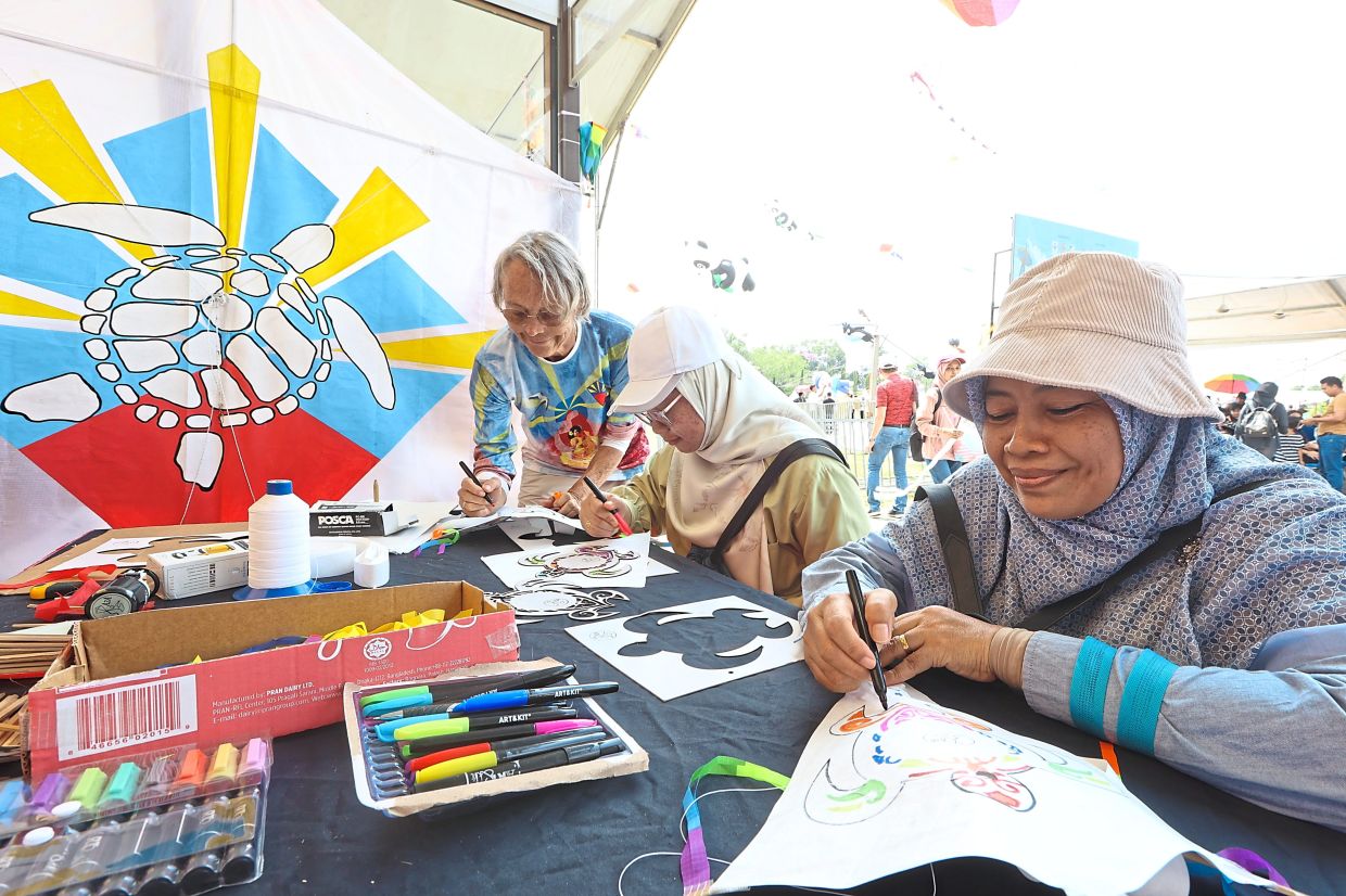 First-time visitor to Pasir Gudang, Corrine Galadie, 58, (standing, left) from Saint Pierre in Reunion Island, teaching participants how to make paper kites with sea turtle design.