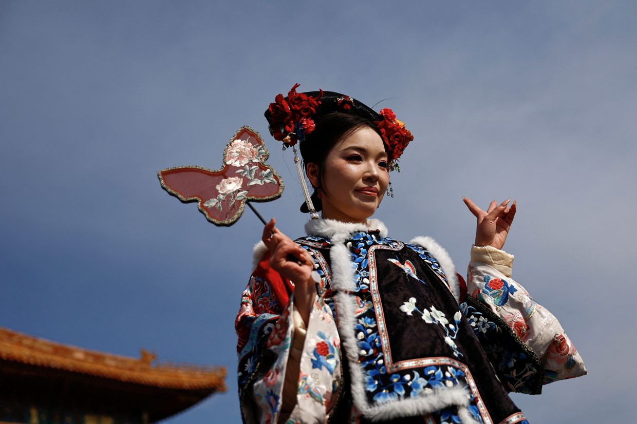 A woman dressed up in a Chinese traditional costume poses for pictures at the Forbidden City in Beijing, China on Friday, February 21, 2025. -- REUTERS/Tingshu WangA